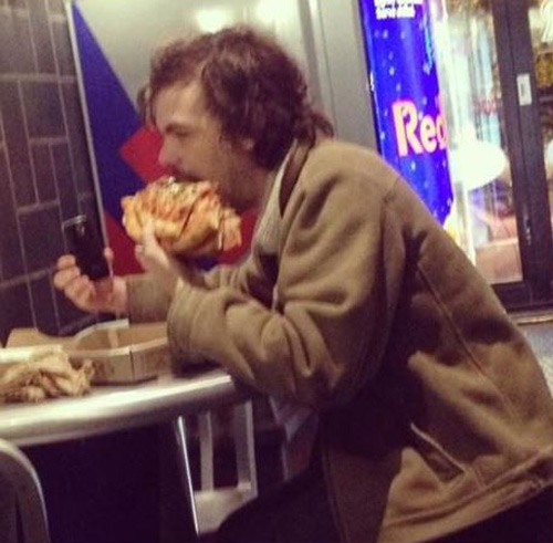 A man eating four slices of pizza and taking a selfie