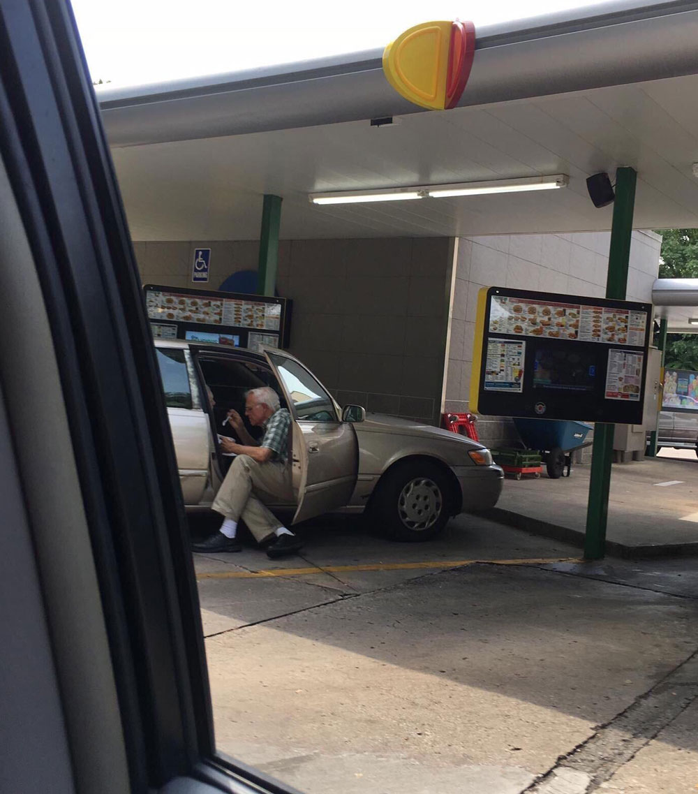 This elderly man spoon feeding his wife ice cream at sonic while they are both in the passenger seat