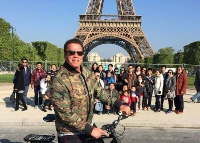 Tourists trying to take a picture at the Eiffel Tower get photobombed by a cyclist