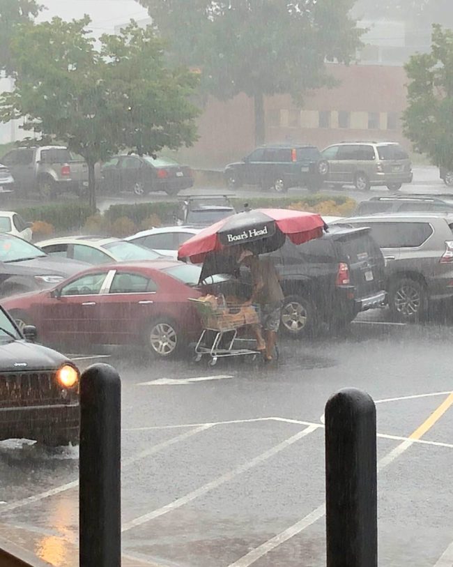 Guy takes the grocery store picnic table umbrella to load his groceries. 10/10
