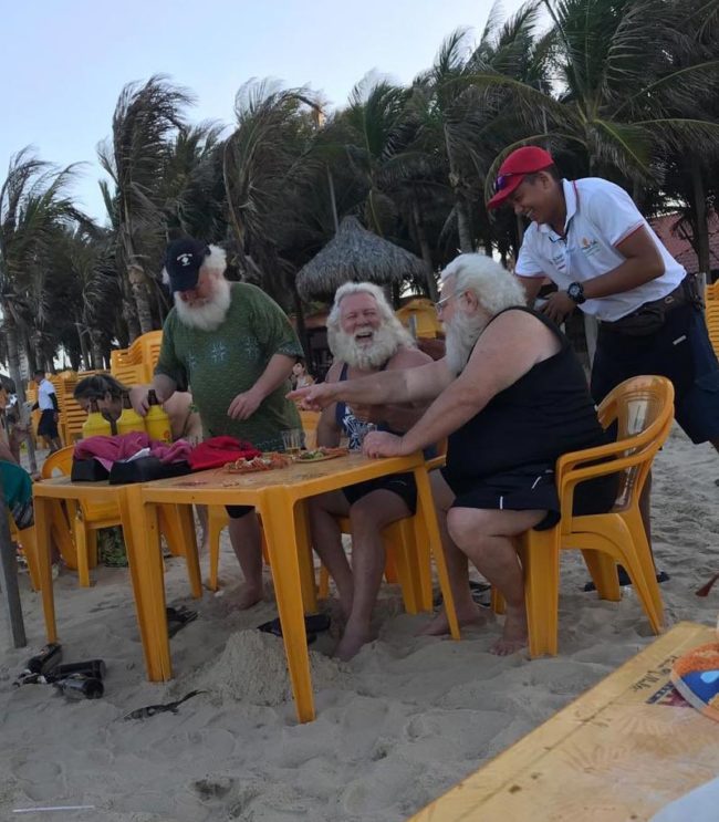 3 Santa's from a mall having a beer on the beach