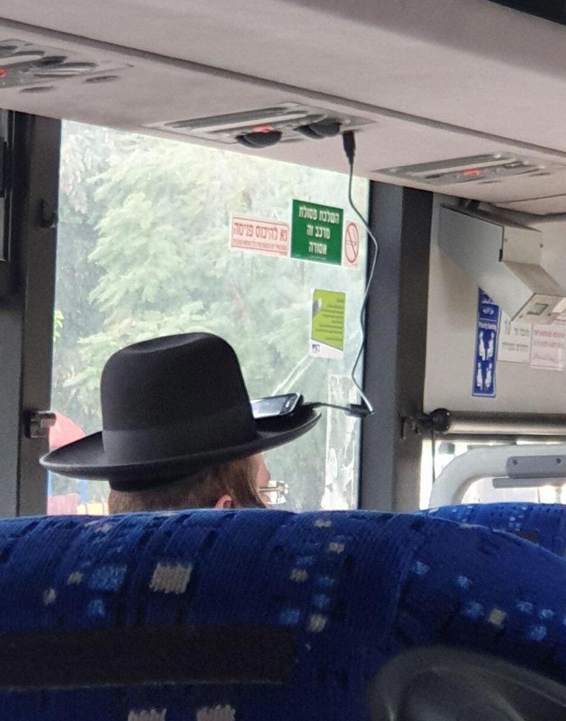 Guy charging his phone on the bus