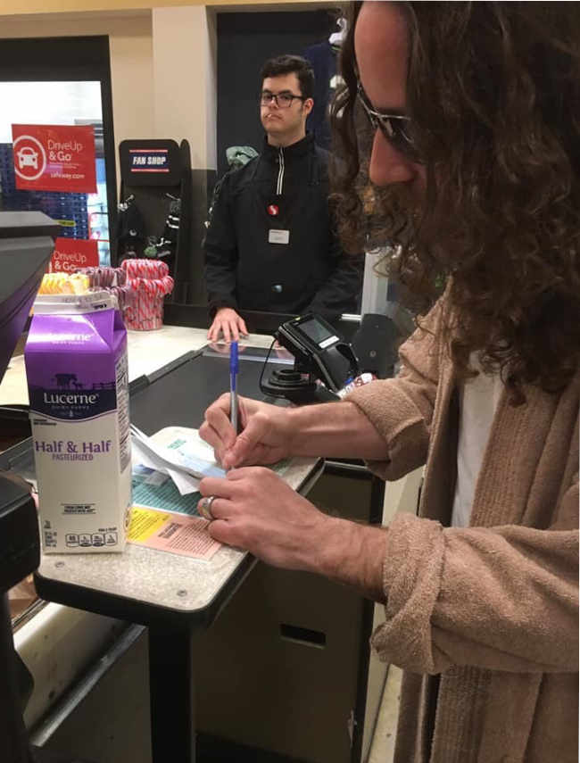 Friend buying half & half with a check at the grocery store on Halloween