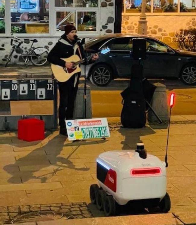 True sentience reached. A delivery robot decided to skip on work and listen to a street musician instead