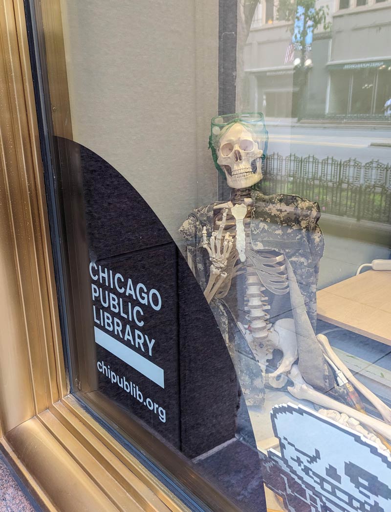 At the Chicago Public Library, there is a skeleton sitting in a display window flicking off the passersby