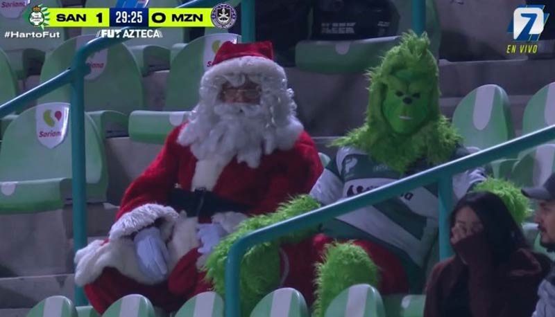 Santa Claus and Mr. Grinch hanging out at a Liga MX match on a Thanksgiving night