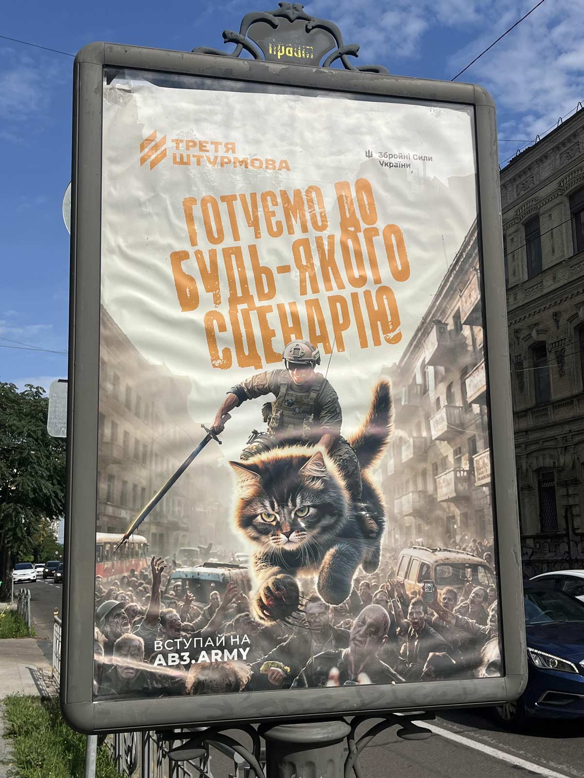 This Ukrainian army recruitment poster has a soldier riding a kitten over an army of zombies